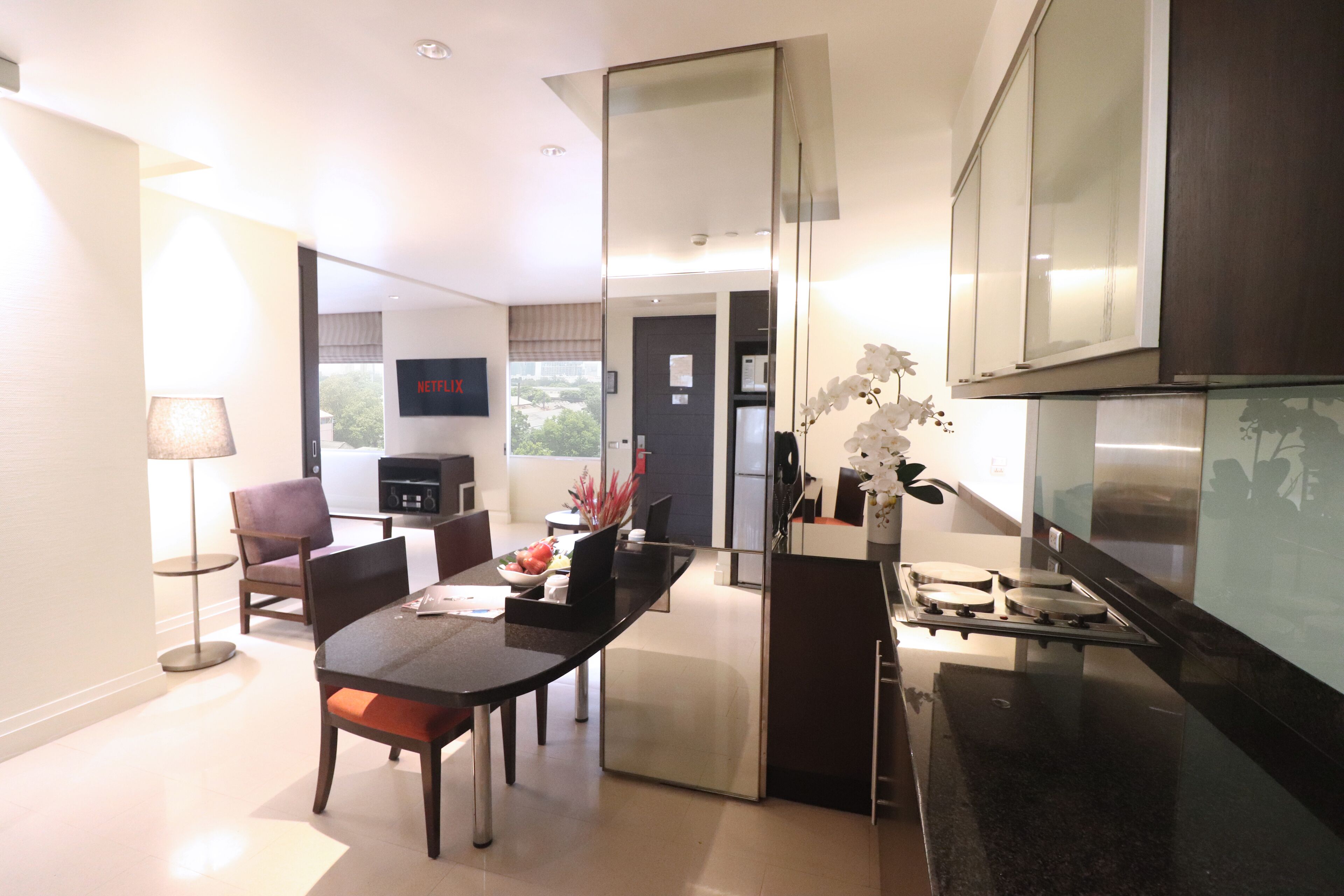 A modern kitchen with a dining area, a flat-screen TV, and a view of the city.