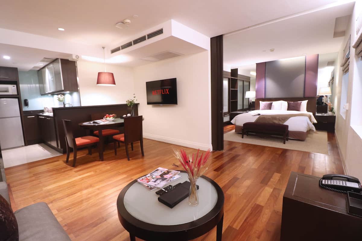 Una habitación de hotel moderna con comedor, kitchenette y una cama grande.