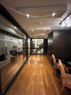 A modern interior with wooden flooring, a seating area with striped chairs, and a visible salon with a glass door. - The Quarter Saladaeng by UHG  (Bangkok)