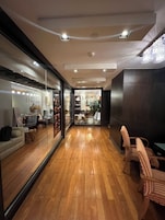 Een modern interieur met houten vloeren, een zithoek met gestreepte stoelen en een zichtbare salon met een glazen deur.