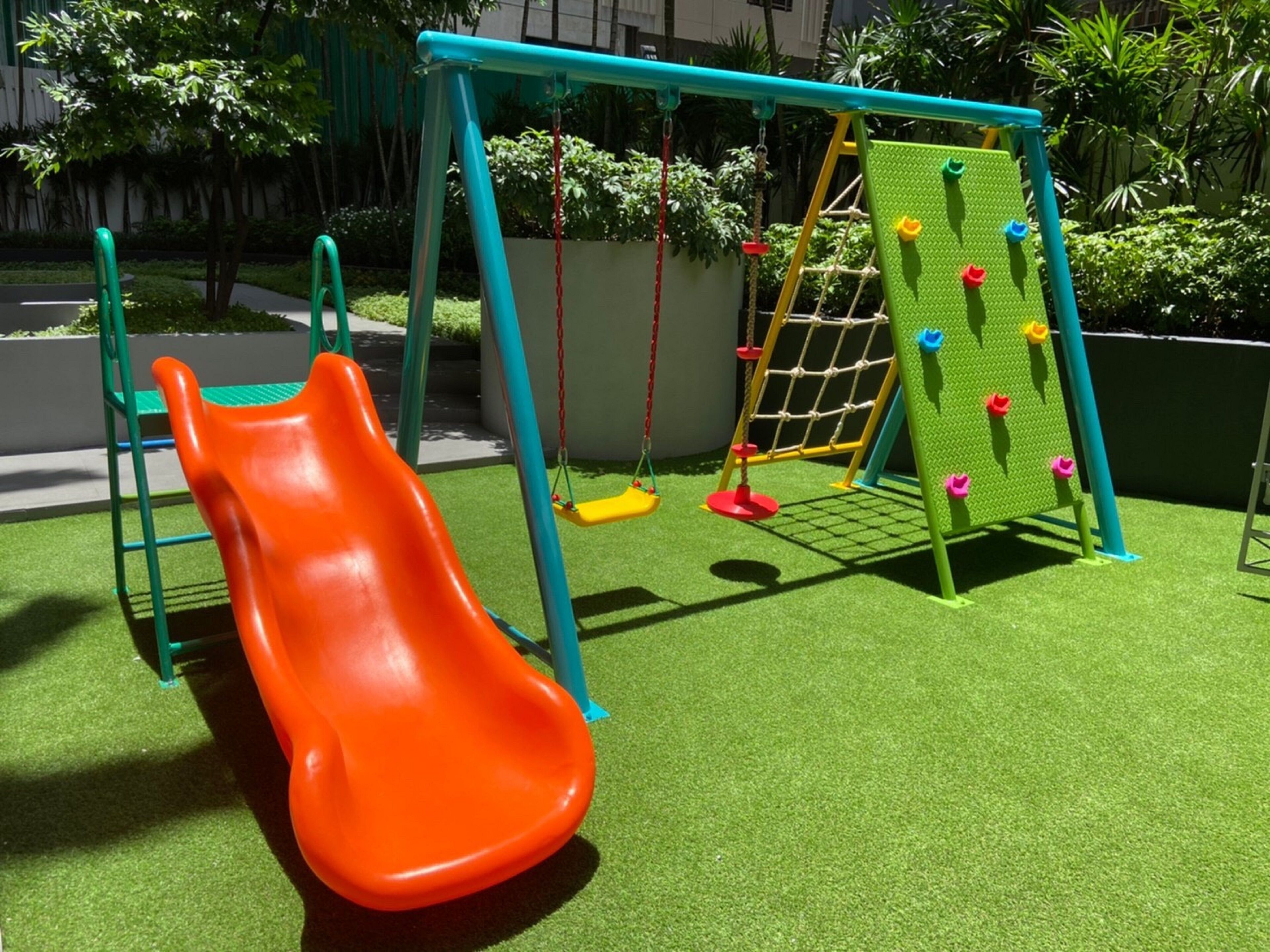 Un parque infantil con tobogán, columpios y una red de escalada.