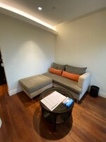 A modern living room with a sectional sofa, a round coffee table, and a small trash can.