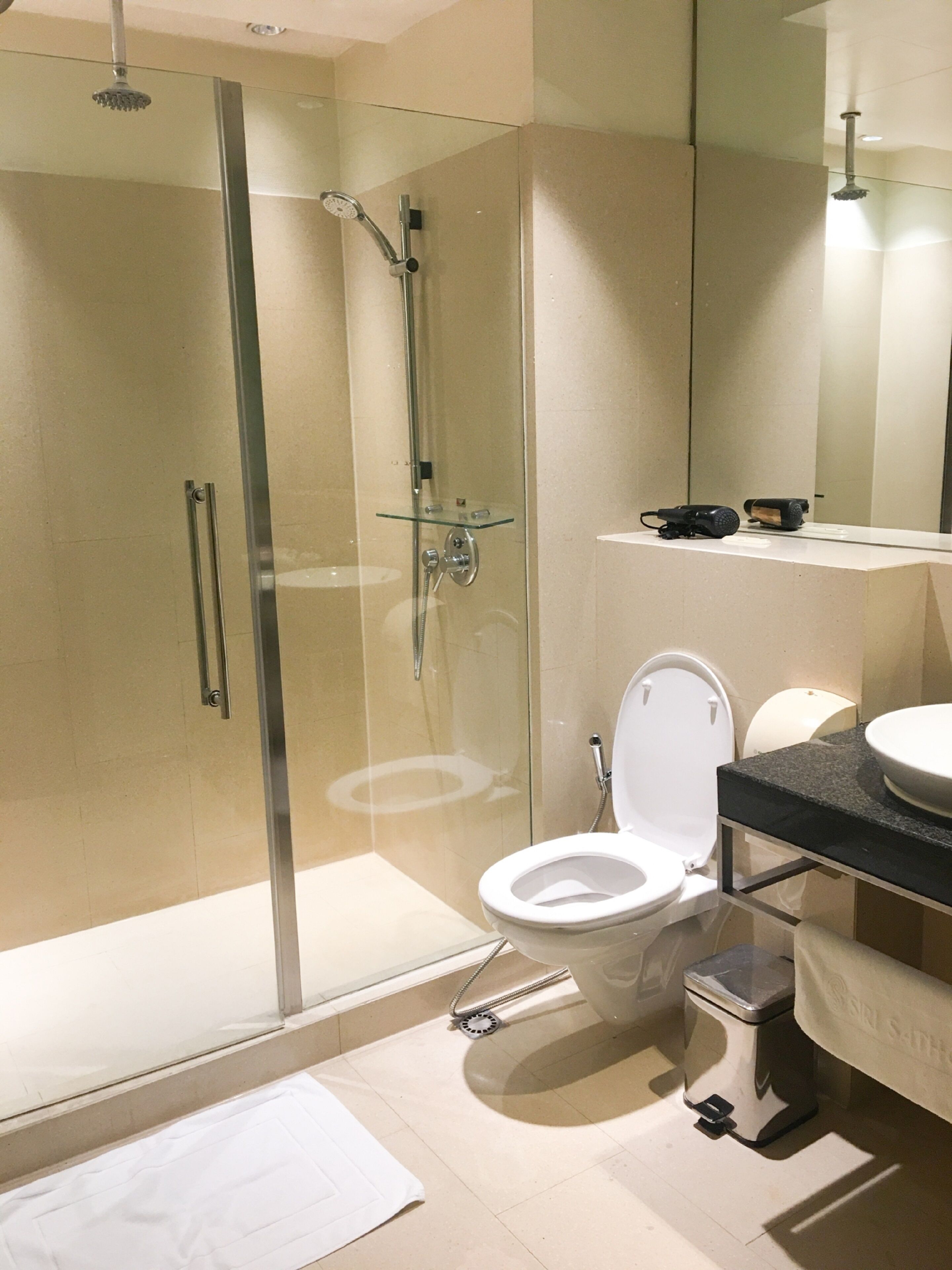 Un baño moderno con ducha de vidrio, inodoro y lavamanos con encimera negra.