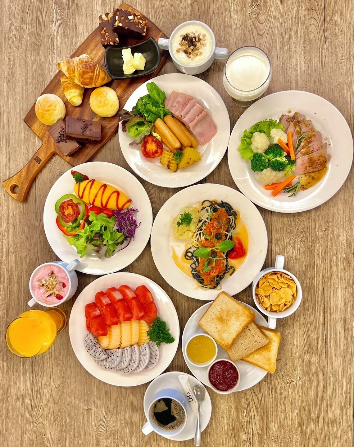 Diversos platos para el desayuno, incluyendo croissants, huevos, y un plato con jamón, vegetales y un bistec.