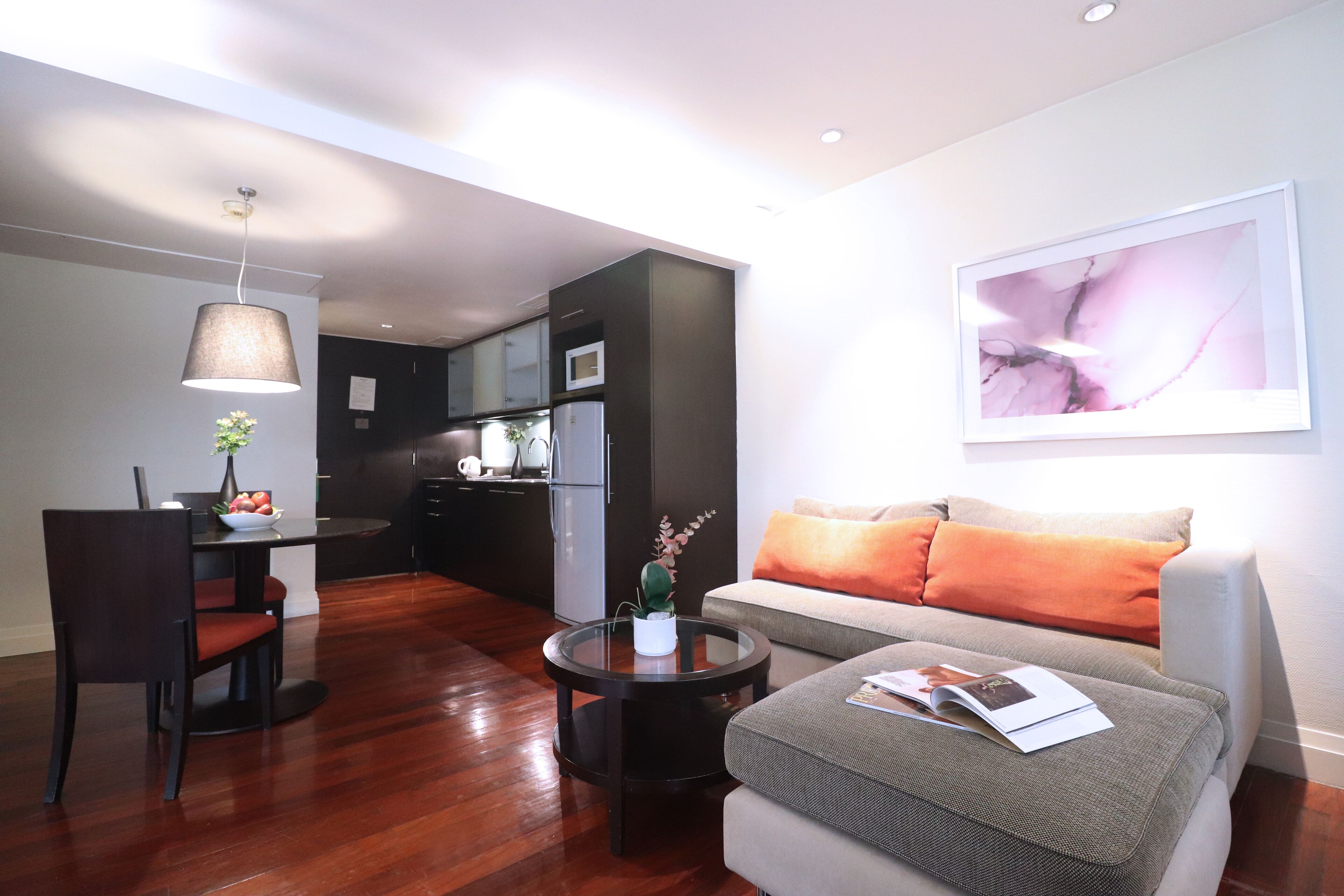 Una sala de estar moderna con un sofá, una mesa de comedor y una cocina al fondo.