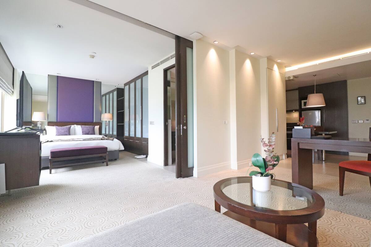 Una habitación de hotel moderna con una cama, una mesita de noche y una pequeña mesa redonda con una planta.