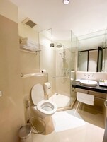 Un baño moderno con ducha de vidrio, inodoro y lavamanos con espejo.