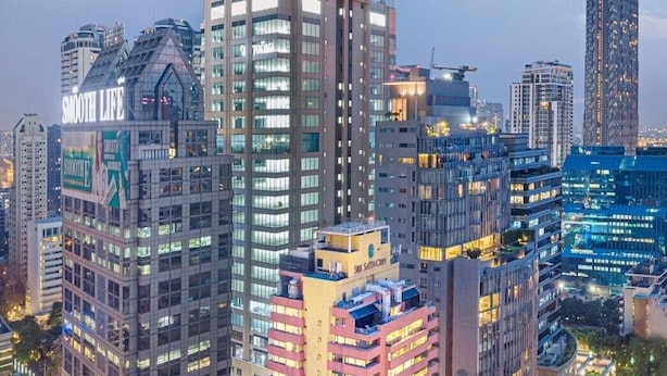 A high-rise building with multiple floors, large windows, and a prominent tower with a spire.