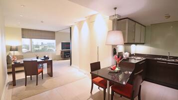 Una habitación de hotel moderna con zona de comedor, cocina y un amplio ventanal con vista a la ciudad.