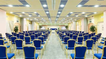 Una sala conferenze con file di sedie blu e un corridoio centrale.