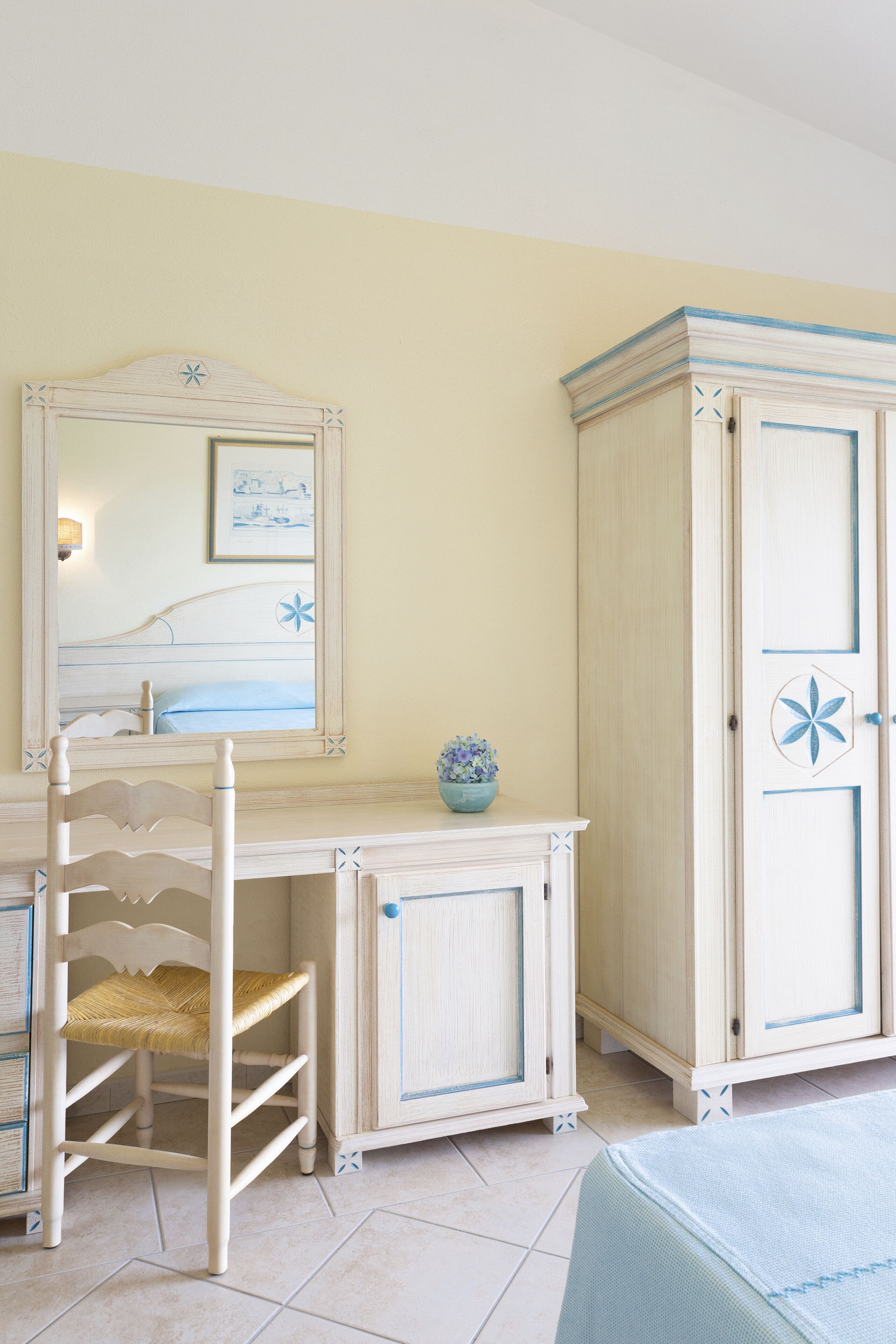 A room with a wooden desk, a chair, a wardrobe, and a mirror.
