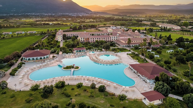 A resort with multiple swimming pools, a large building complex, and surrounding green landscapes. - Club Hotel Marina Beach (Orosei)