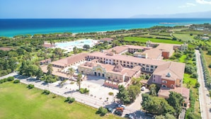 An aerial view of a resort with a large building, a swimming pool, and a view of the ocean. - Club Hotel Marina Beach (Orosei)