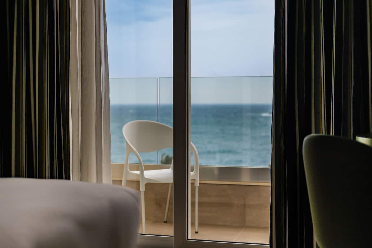 A hotel room with a balcony overlooking the sea.