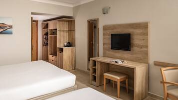 A hotel room with two beds, a wooden desk with a chair, a TV mounted on the wall, and a wardrobe.