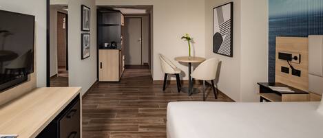 Habitación de hotel con cama, escritorio, silla, mesita y televisión.