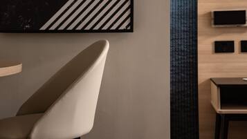Een modern interieur met een minimalistische stoel, een zwart-wit kunstwerk en een klein tafeltje met een televisie.