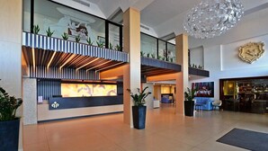 A modern lobby with a reception desk, seating areas, and a bar.