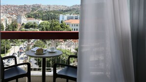 A balcony with a table and chairs, overlooking a cityscape with buildings and trees. - Hotel Abc (Thessaloniki)