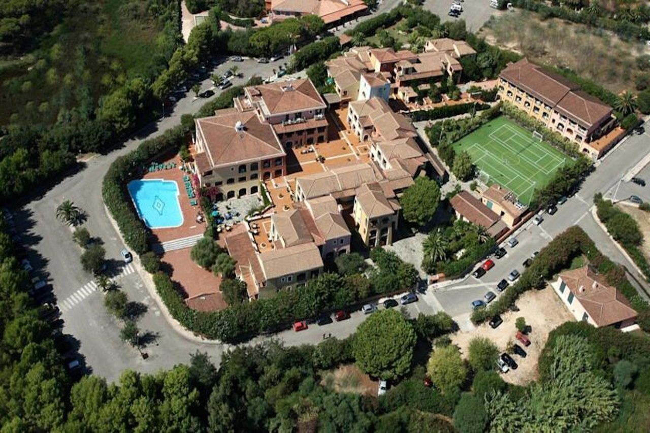 Vista aerea di una zona residenziale con diversi edifici, una piscina e un campo da tennis.