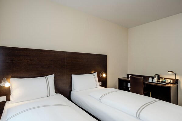 A hotel room with two beds, a desk, and a chair.
