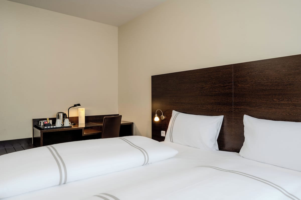 A hotel room with a large bed, a desk with a lamp, and a nightstand.