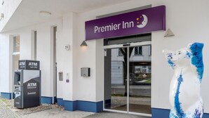 A Premier Inn entrance with an ATM machine, a glass door, and a blue and white sculpture.