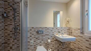 Ein Badezimmer mit Dusche, Toilette, Waschbecken und Spiegel.