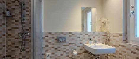 A bathroom with a shower, toilet, sink, and a mirror.
