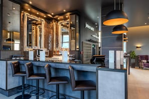 A modern bar area with a counter, bar stools, and a large mirror.