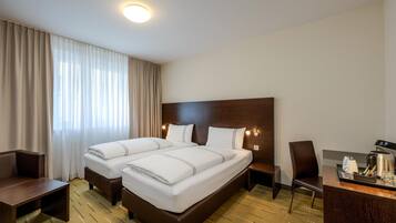 Camera d'albergo con due letti, una scrivania, una sedia e una macchina per il caffè.