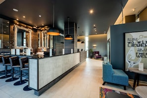 A modern bar area with a counter, multiple mirrors, and bar stools. - Premier Inn Berlin City Spittelmarkt (Berlin)