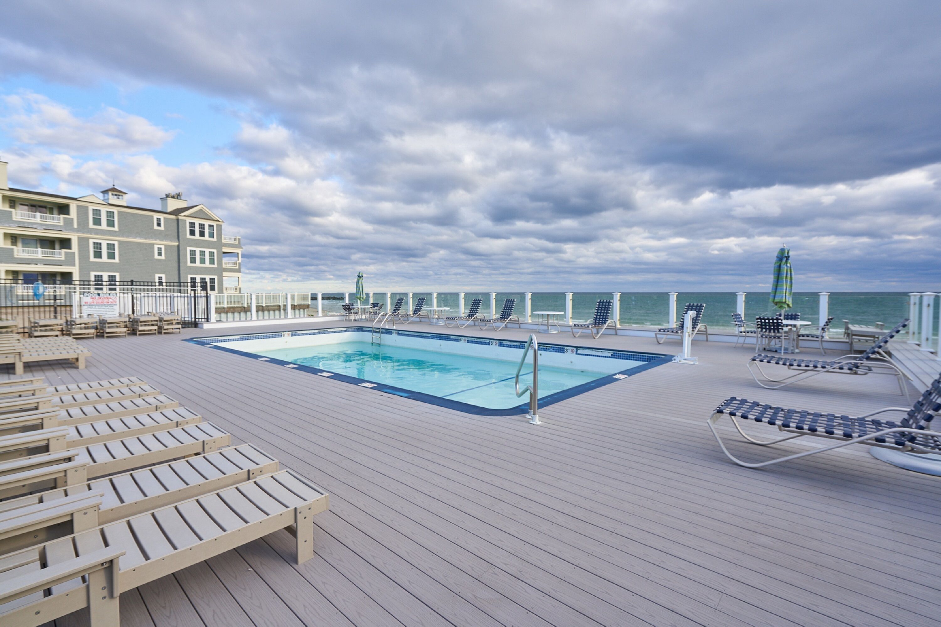 Ein Poolbereich mit Liegestühlen und Blick auf den Ozean.