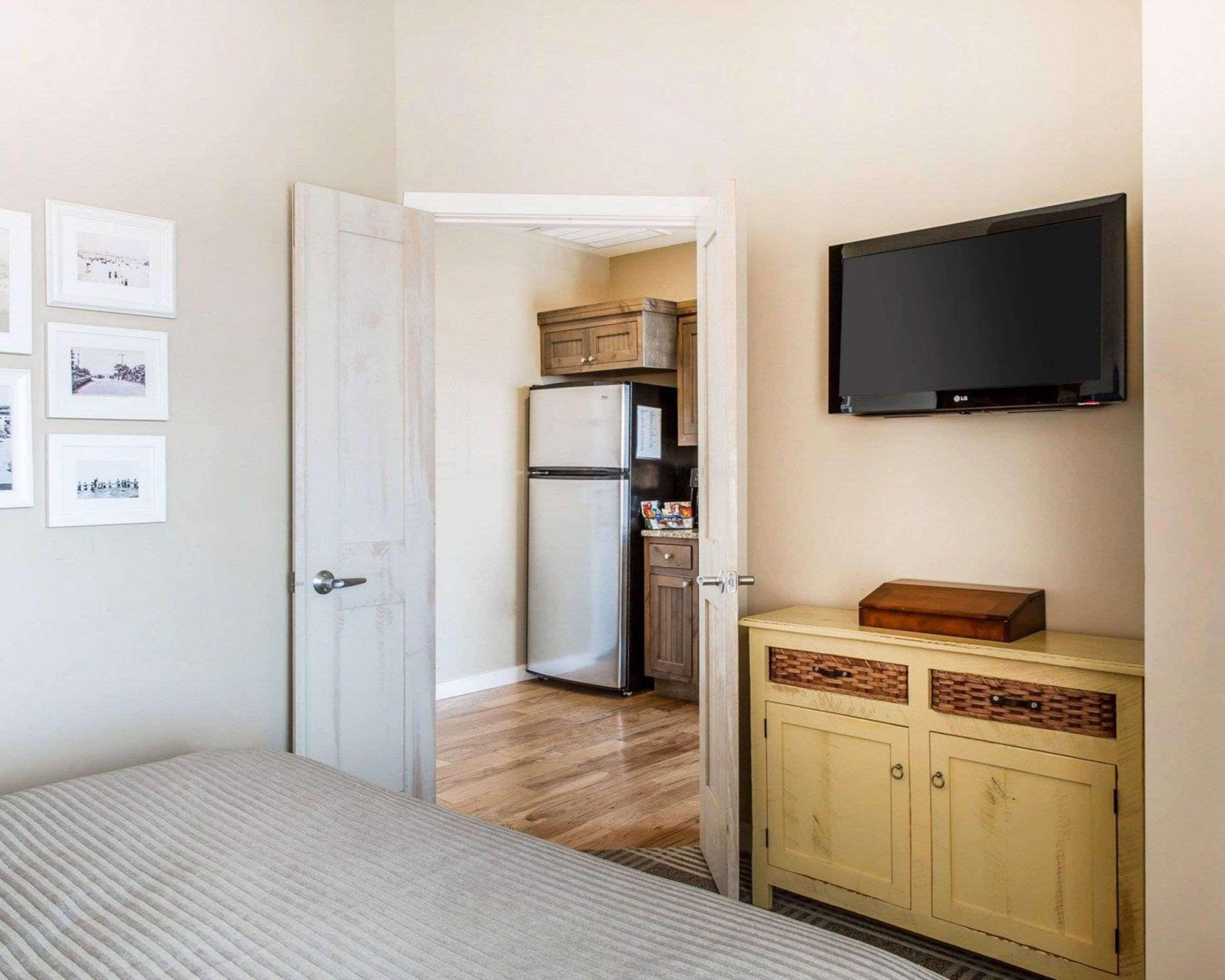 Ein Schlafzimmer mit Bett, Kleiderschrank, Fernseher und einer Tür zu einer Küche.
