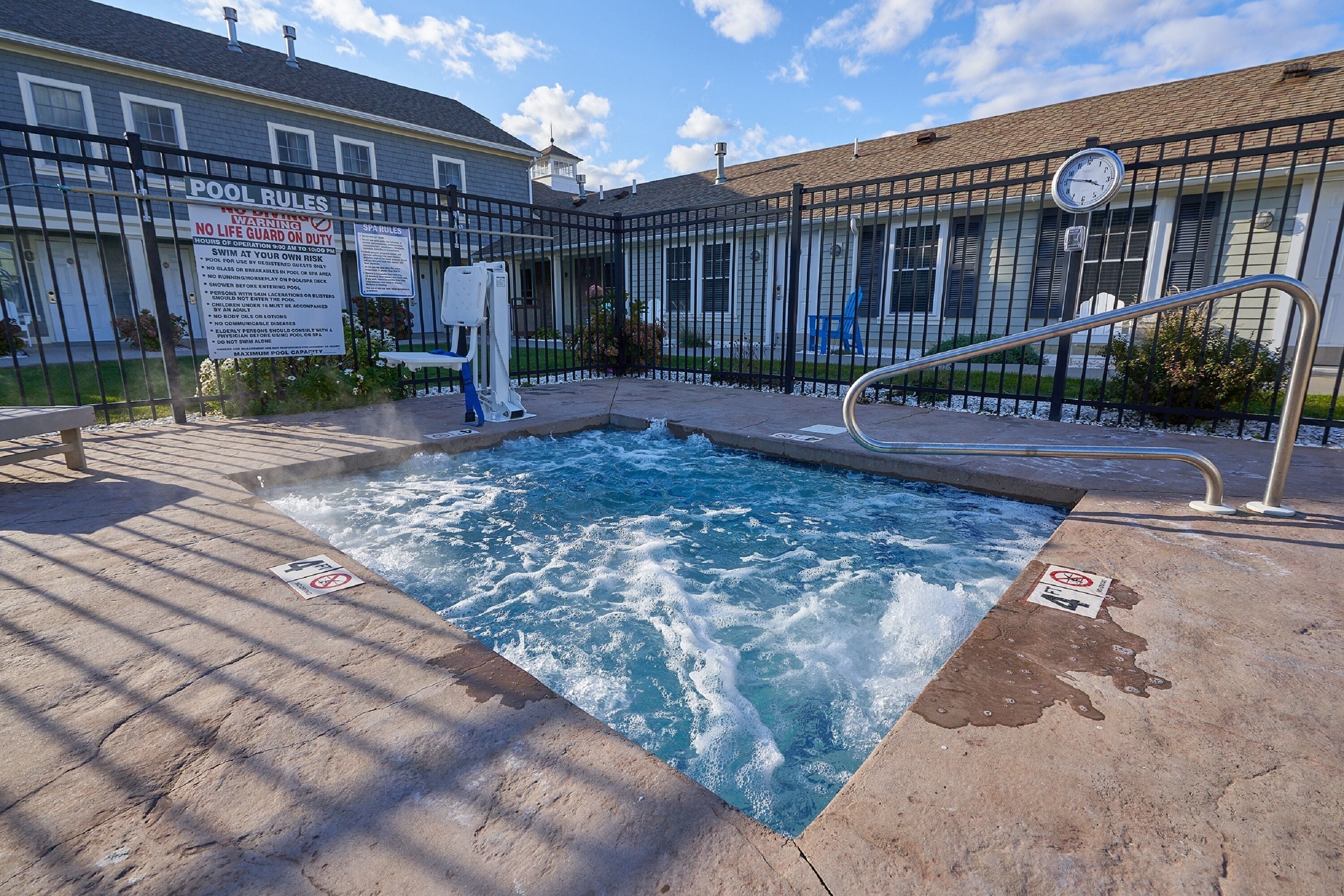 A hot tub with a metal railing and a sign indicating pool rules.