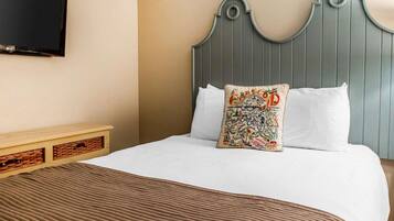 Una cama bien hecha con un edredón marrón, un cabecero gris y dos almohadas, una con un diseño colorido.
