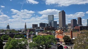 Une vue sur les toits d’une ville, avec des bâtiments modernes, une structure en forme de dôme et un ciel bleu dégagé.