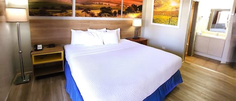 A hotel room with a large bed, a wooden headboard, and two paintings on the wall.