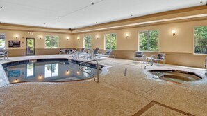 Una piscina interior con sillones de descanso y un jacuzzi.