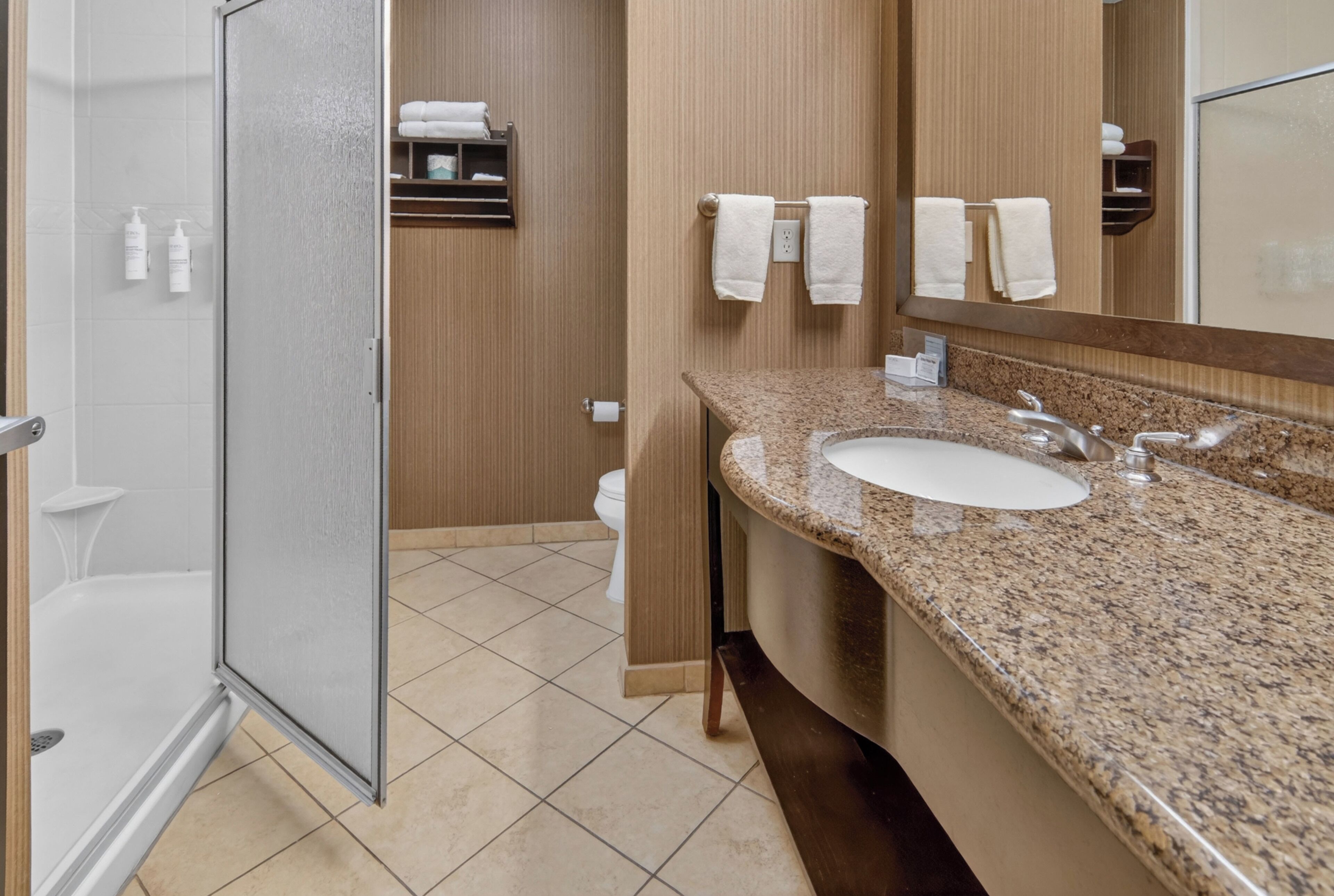 A bathroom with a shower, toilet, sink, and towel rack.