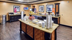 A hotel breakfast area with a buffet counter, microwave, and various food items.
