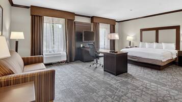 A hotel room with a bed, a desk, a chair, a TV, and a lamp.