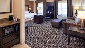 A hotel room with a bed, desk, chair, sofa, and a television.