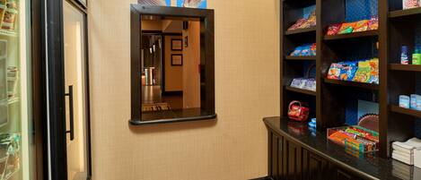 A hotel hallway with a vending machine, a mirror, and a snack display.
