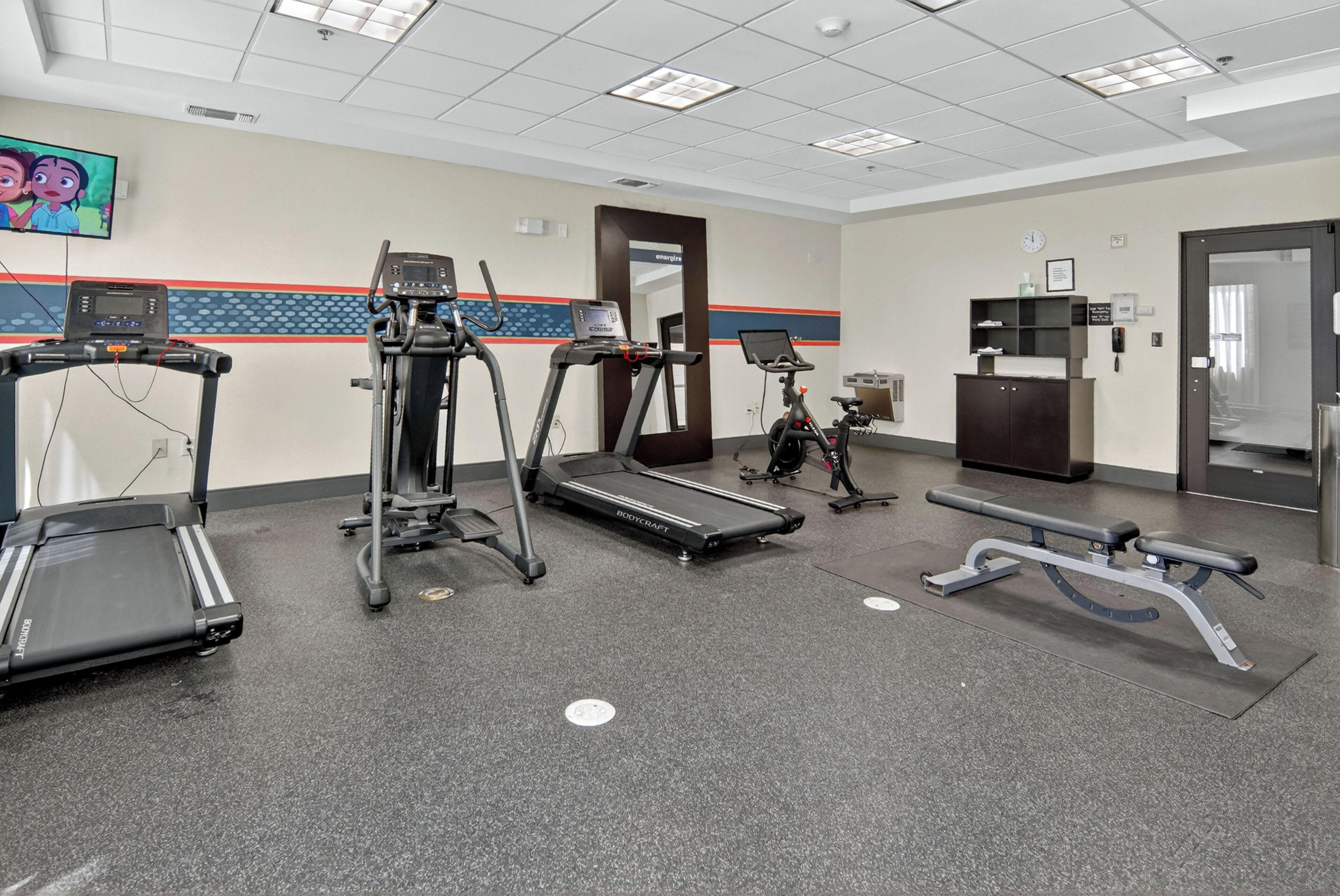 A gym with treadmills, elliptical machines, and a bench press.
