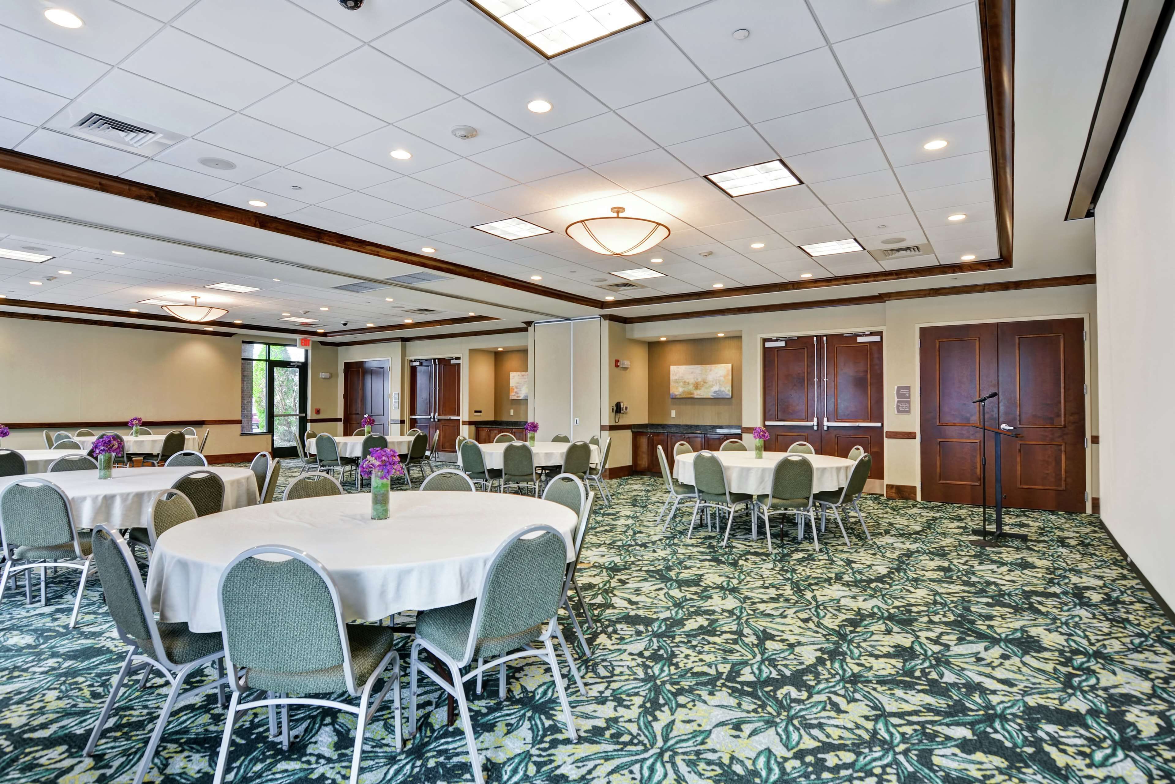 A conference room with round tables, chairs, and a carpeted floor.