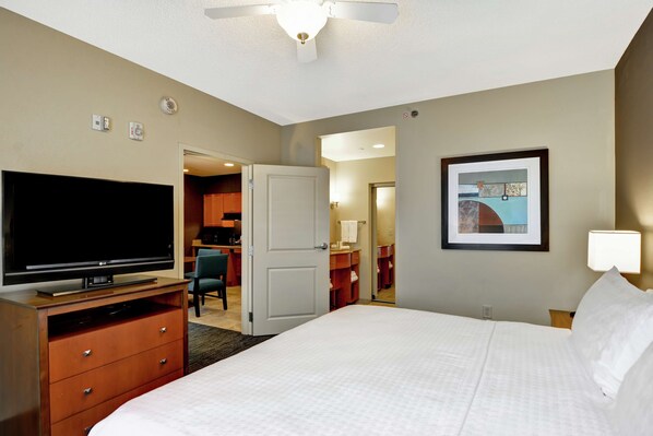 Una habitación de hotel con cama, televisor, cómoda, escritorio y silla.