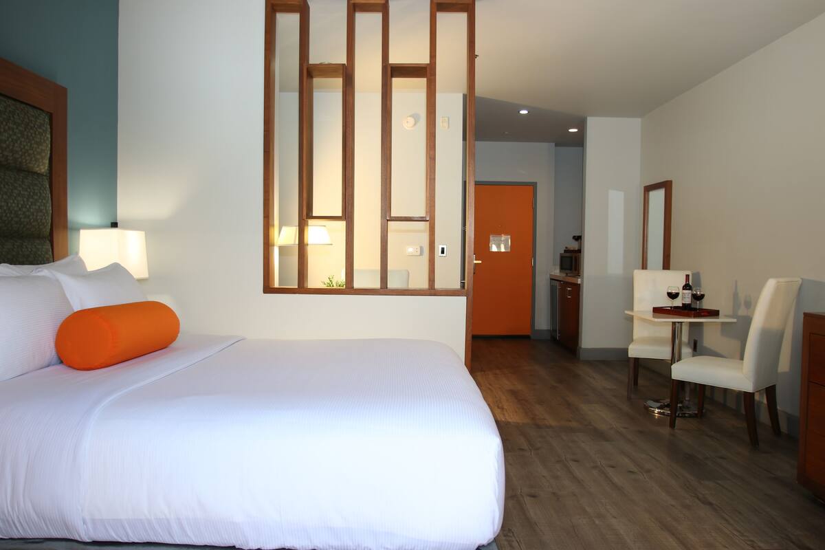 Een hotelkamer met een groot bed, een bureau met stoel en een zithoek.