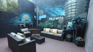 An outdoor seating area with wicker furniture, a coffee table, and potted plants. - BLVD Hotel and Studios Universal-Hollywood, an Ascend Collection Hotel (Studio City)
