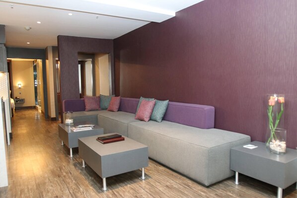 Una sala de estar moderna con un sofá seccional gris, una mesa de centro y una mesita auxiliar con un jarrón.